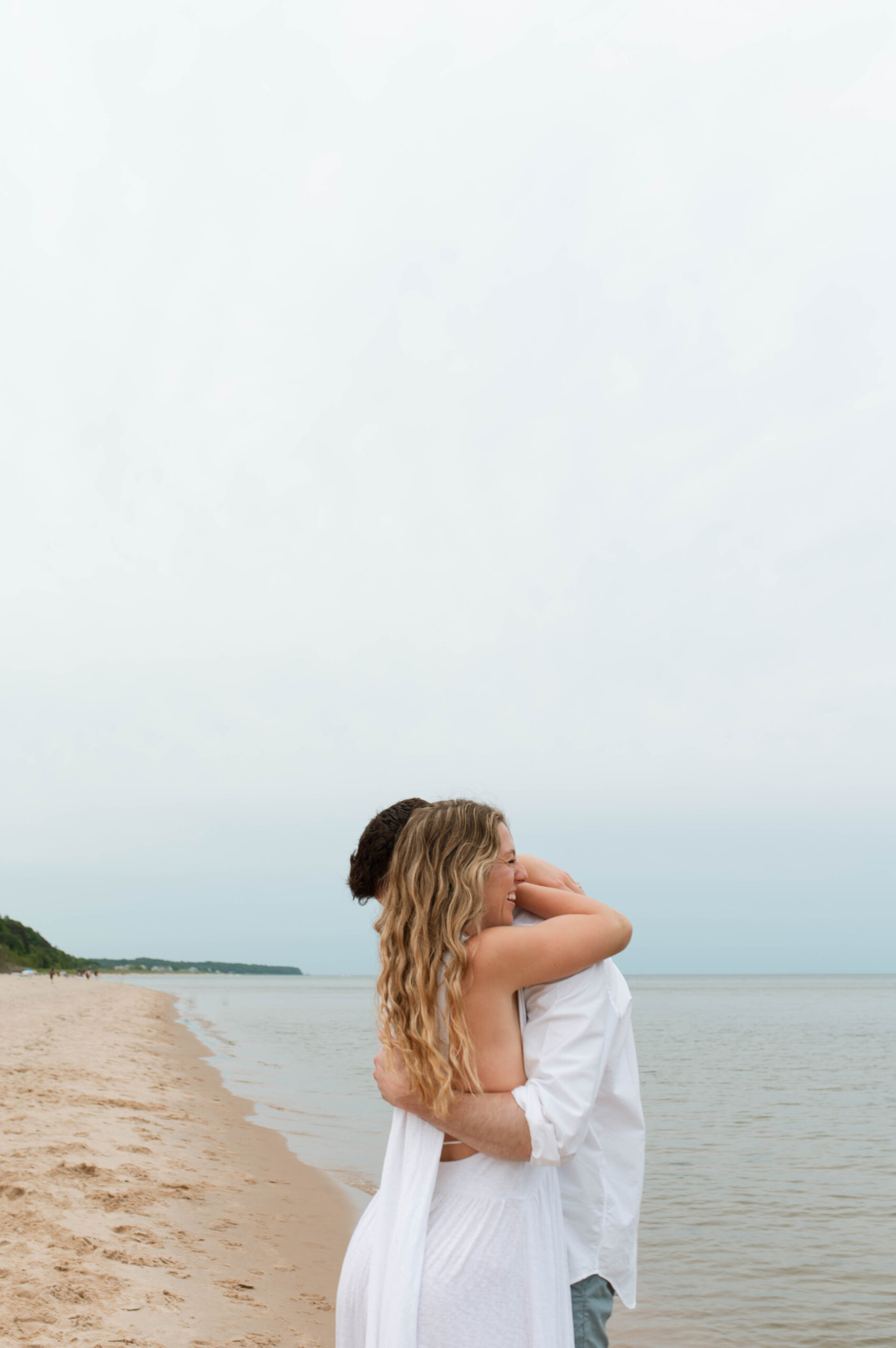 A joyful couple has their engagement session on the shoreline of Lake Michigan at Saugatuck Dunes State Park.
