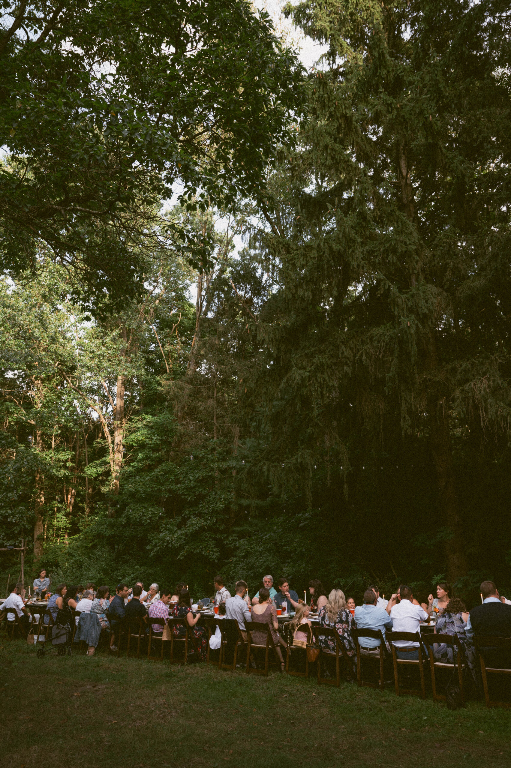 A long table full of friends and family enjoying dinner together at an outdoor michigan wedding.