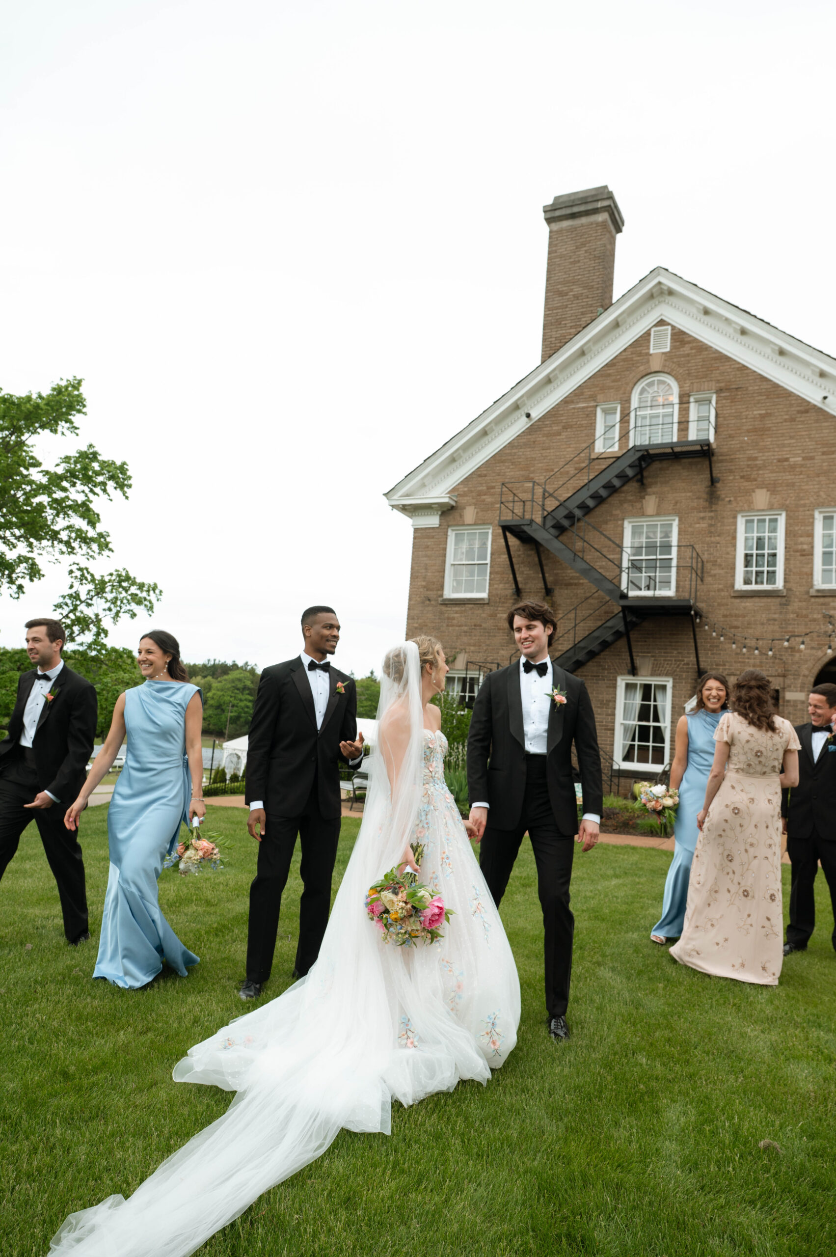 A candid photo of a bride and groom surrounded by their wedding party in front of their michigan wedding venue.